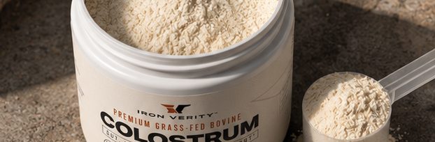 An open jar of colostrum beside a filled measuring scoop of cream-coloured powder.